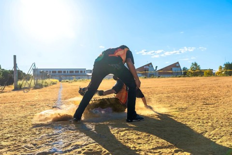Two baseball players in action on a dirt field, with one player sliding headfirst into a base,