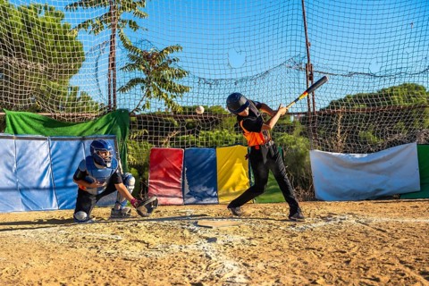 Young baseball players honing their skills, with a batter swinging a bat to hit a flying ball and a