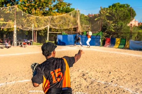 Players on a dusty baseball field engaging in a competitive game, with a pitcher winding up to