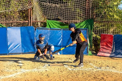 Youth baseball players, a batter taking a swing at a pitch and a catcher ready behind home plate,