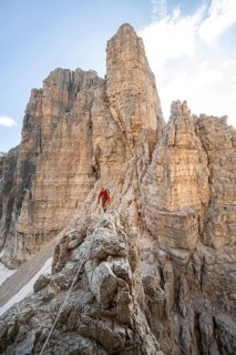 Mountaineer climbs an exposed rock in the secured Via Ferrata Bocciere Centrale via ferrata,