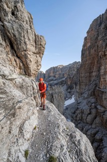 Mountaineer climbs an exposed rock band in the secured via ferrata Bocciere Centrale, Brenta