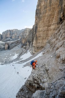 Mountaineer climbs on an exposed rock in the secured Via Ferrata Bocciere Centrale via ferrata,