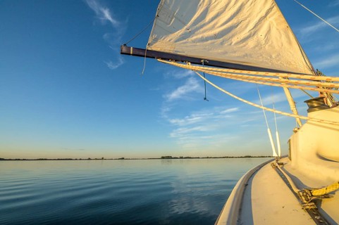 Sailing boat dinghy cruiser on calm Dümmer See, wide horizon, clear blue sky tint, Dümmer nature