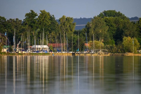 Dümmer See with sailboats and trees on the shore, harbor view with reflections of boats and masts,