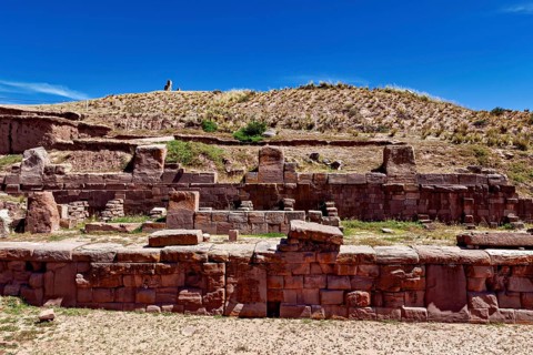 Ancient stone ruins under a clear blue sky surrounded by dry, grassy landscape, The archaeological