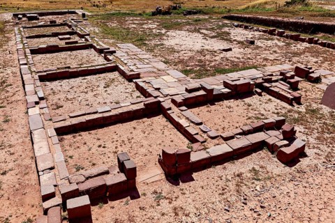 Floor plans of stone ruins in an open area under clear skies, The archaeological site with the