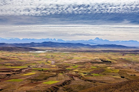 Wide panorama with fields and mountains under a cloudy sky, The Altiplano landscape in the Andes of