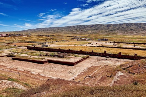 Extensive valley with ruins in the foreground and a mountain range on the horizon, the