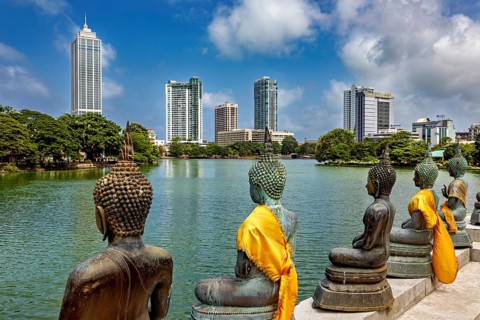 Bronze Buddha statues with yellow cloths look at the skyline of a city, the Seema Malaka temple