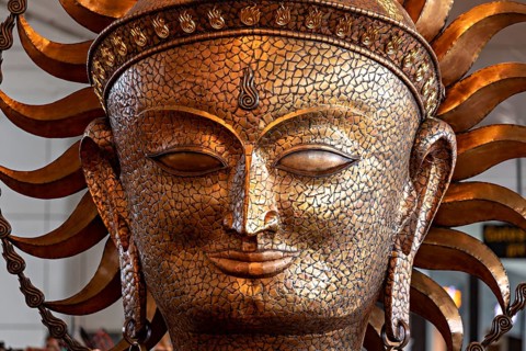 Golden sculpture of a face with solar elements, ancient art style with ornate details, portrait of