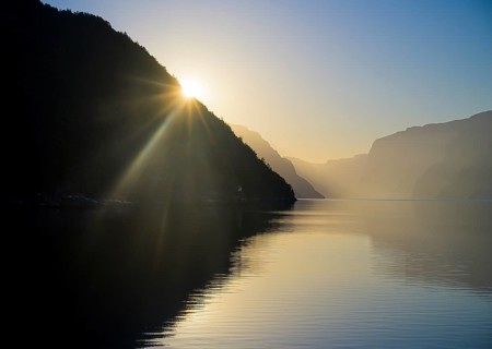 Sunset over the early morning Lysefjord with silhouetted mountains and a warm atmosphere, near