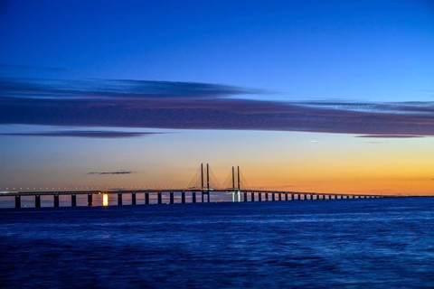 Modern Øresund bridge across the sea at sunset with colorful sky illuminated by a colorful sunset,