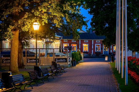 Illuminated alley in the old town of Naantali with benches and trees at dusk, cozy atmosphere,