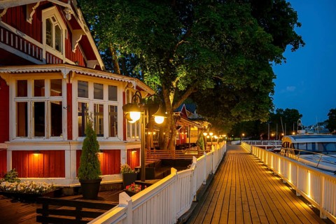 Wooden walkway promenade with red wooden house on an illuminated promenade at dusk, cozy atmosphere
