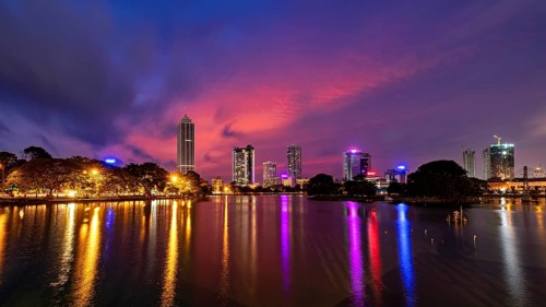 City landscape at night with impressive lights and colorful sky above the water surface, the