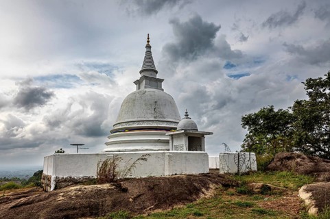 White stupa against dramatic sky surrounded by natural terrain, tranquil atmosphere, The