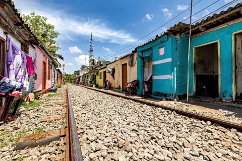 Empty railroad line lined with colorful houses lined up under cloudy sky, railway line in the