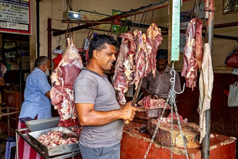 A butcher stands in a traditional meat shop, pieces of meat are on display, bustling atmosphere,