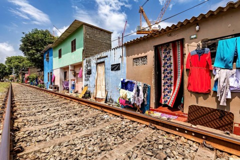 Colourful houses along railroad tracks with clothes hung up in an urban setting, railway line in