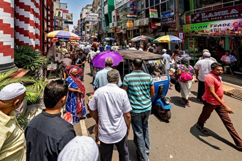 People and rickshaws on a colorful, busy street in the sunshine, in the streets of the old town of