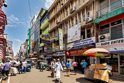 Busy shopping street with lots of people and colorful signs in sunny weather, In the streets of the