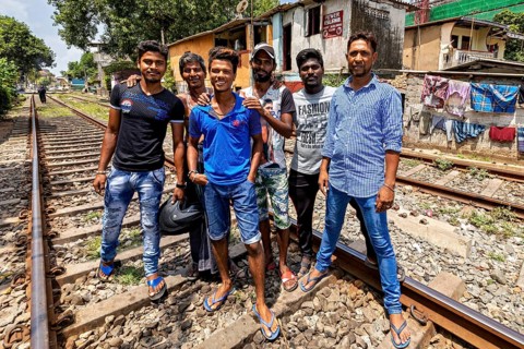 Group of men pose on railroad tracks in an urban setting, showing friendship and smiles, friends on