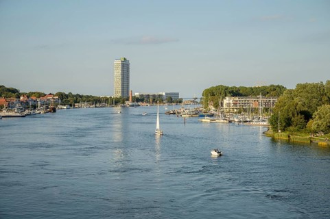 The river Trave crosses the city with a high-rise building and boats just in front of it flows into
