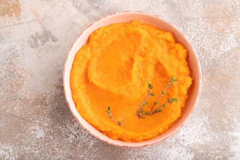 Sweet potato porridge in ceramic bowl on brown concrete background. Diet, healthy eating concept.