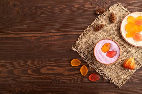 Purple Yogurt, with jelly candy on brown wooden background and linen textile, top view, flat lay,