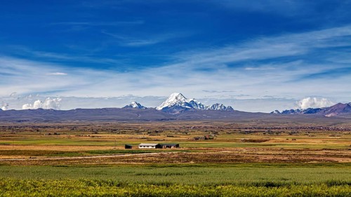 Green fields in the foreground with snow-covered mountain in the distance, The landscape of the