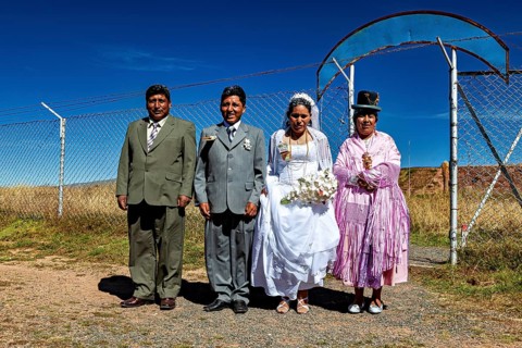 Wedding couple and companions in traditional clothes in front of fence and blue sky, traditional
