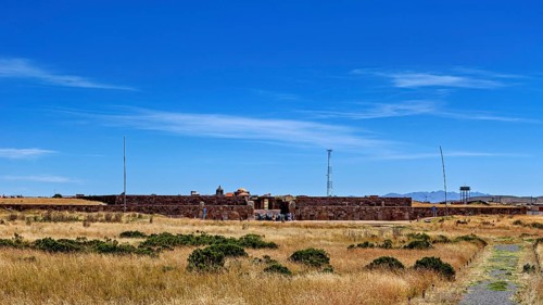 Stone ruins surrounded by pristine meadow and clear skies, evoke a sense of vastness, The