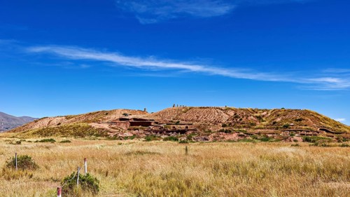 Meadow hill with traces of ruins, under wide blue skies, highlights the natural beauty of the