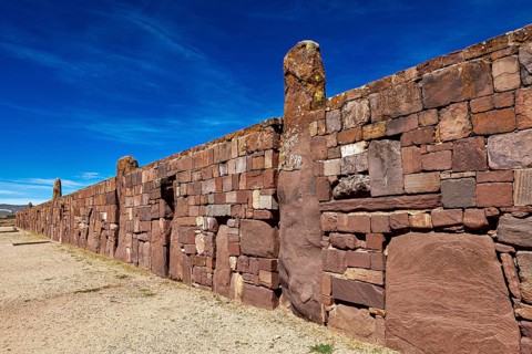 Ancient stone wall stretching along a narrow path under blue sky, the archaeological site with the
