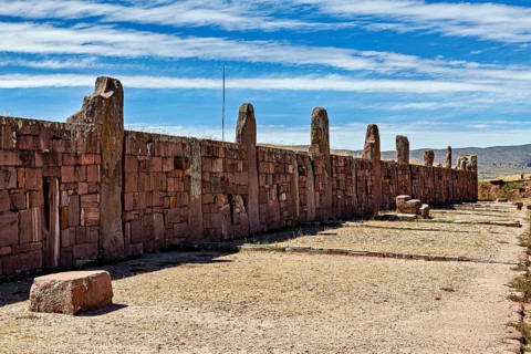 Long stone wall with standing stones under a slightly cloudy sky, The archaeological site with the