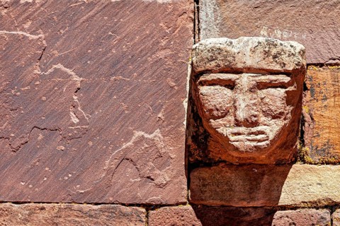 Head engraved in stone in an old wall illuminated by strong sunlight, The archaeological site with