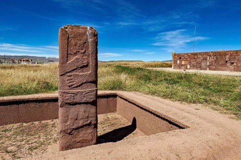 Upright ancient stone column in scenic surroundings under blue sky, The archaeological site with