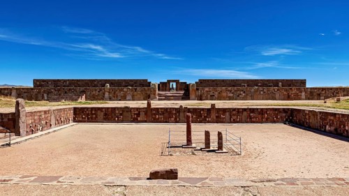 Open ruins with stone walls and sandy soil under a clear blue sky, The archaeological site with the