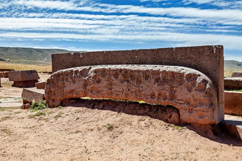 Ancient stone monument with mysterious engravings, lying under a cloudy sky in quiet surroundings,