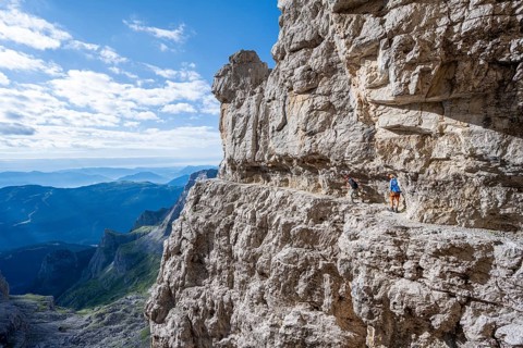 Two mountaineers on an exposed rock band in the secured via ferrata Bocciere Centrale, Brenta