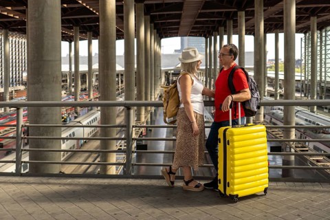 Middle aged couple enjoying a travel moment at a busy train station while waiting for their train.