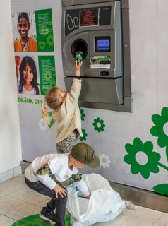 Two children, 5 and 7 years old, earn pocket money by recycling cans in a recycling machine in