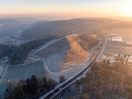 Small hill surrounded by wooded landscape in the light of the evening sun, old deposit,