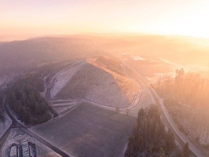 Snowy hill in soft morning light, surrounded by fog, old deposit, construction site for PV open