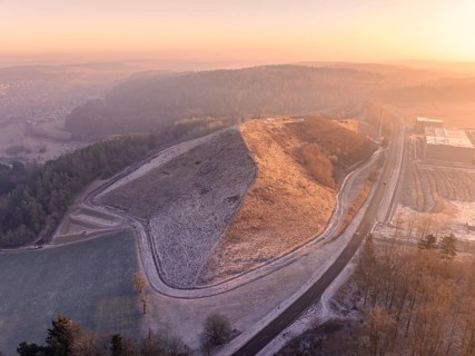 Hillside area at sunset with golden light and snowy paths, old deposit, construction site for PV