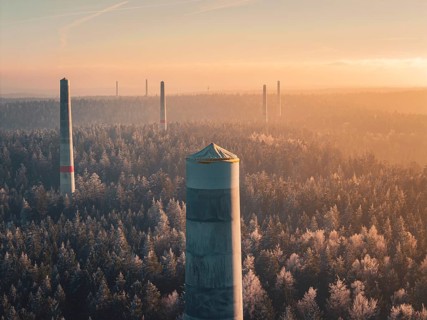 In the distance, smoke-free wind turbine towers stand over thick fog, the winter forest and an