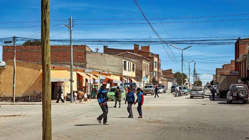 Lively street scene in a small town with passers-by and cars, the city of Uyuni in Bolivia