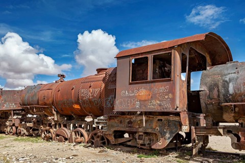 Rusty locomotive with vivid graffiti against a blue, cloudy sky, old rusty locomotives at the train