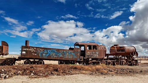 Weathered locomotive in the desert with clouds in the blue sky, old rusty locomotives at the train